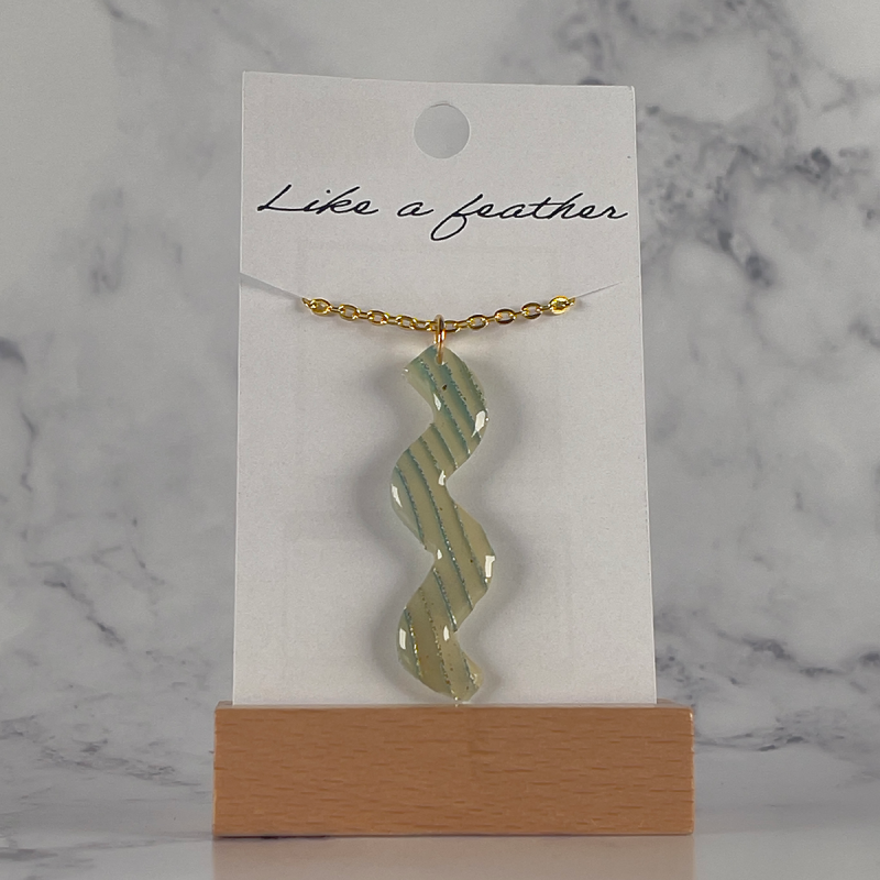 Pendentif en forme de serpentin, de couleurs blanche cassée,
